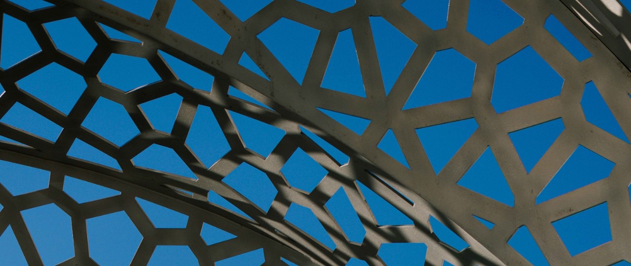 Intricate metalwork in front of blue sky. Image is decorative.